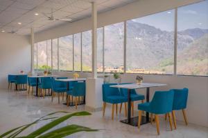 a restaurant with blue chairs and tables and windows at Alpine Retreat in Narendranagar +27 photos
