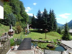 um jardim com um lago e uma ponte de madeira em FeWo Katie em Radenthein