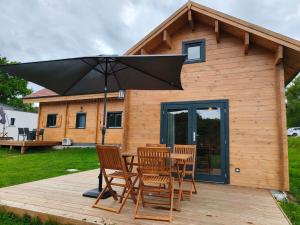 a table and chairs on a deck with an umbrella at Charmant petit chalet jurassien in Saint-Lamain