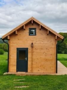 a log cabin with a black door and a window at Charmant petit chalet jurassien in Saint-Lamain