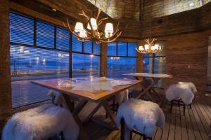 a dining room with a table and chairs and windows at Hotel Costaustralis in Puerto Natales