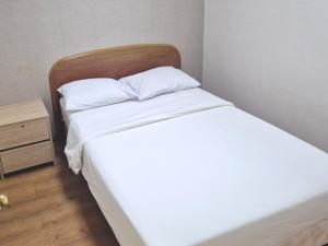 a bed with white sheets and a wooden headboard at Muju Ilsung Condo in Muju