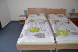 2 Betten in einem Zimmer mit weißer Bettwäsche und grünen Kissen in der Unterkunft Penzion Tučňák in Zábřeh
