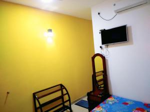 a bedroom with a yellow wall with a bed and a flat screen tv at New Dinu Holiday Inn in Kataragama