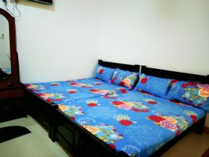 a bed with a blue comforter and two pillows at New Dinu Holiday Inn in Kataragama