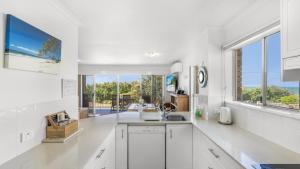a kitchen with white cabinets and a large window at The Calm At Moreton View in Woorim