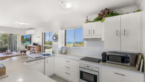 a kitchen with white cabinets and a microwave at The Calm At Moreton View in Woorim