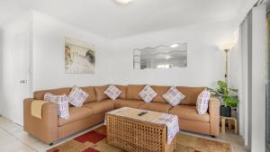a living room with a brown couch and a table at The Calm At Moreton View in Woorim
