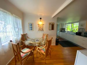 a dining room with a glass table and chairs at Lakeside 3-BR Forest Cottage in Laurieton