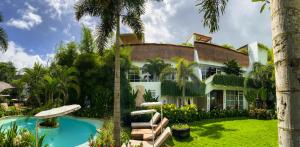 a house with a swimming pool and palm trees at Mantra Wellness Center in Uluwatu