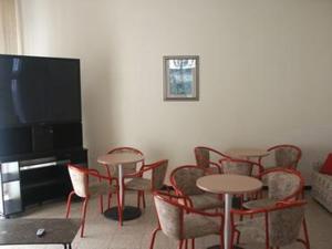 a room with tables and chairs and a flat screen tv at Hotel Mignon in Alassio