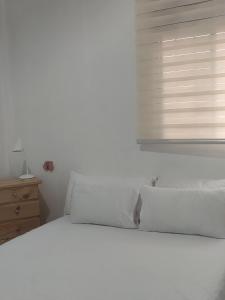a white bed in a bedroom with a window at Pachamic House in Guayaquil