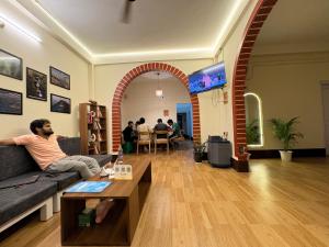a man sitting on a couch in a living room at Yaro Backpackers Hostel in Guwahati