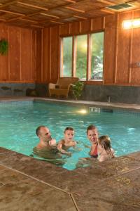 Lake Quinault Lodge في كويناولت: رجل وثلاث اطفال في مسبح