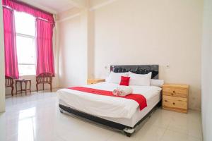 a bedroom with a large bed with pink curtains at RedDoorz near Universitas Merdeka Malang 2 in Malang