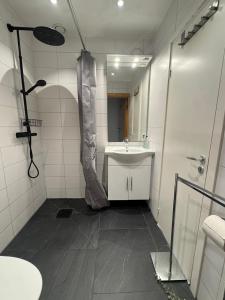 a white bathroom with a sink and a shower at Lägenhet i Limhamn/sibbarp in Malmö