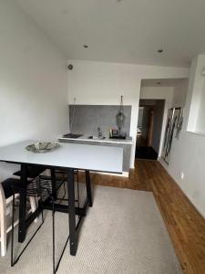 a white kitchen with a table and a sink at Lägenhet i Limhamn/sibbarp in Malmö