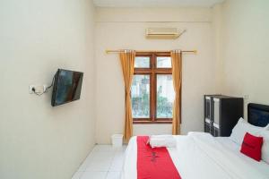 a bedroom with a bed and a window at RedDoorz near Universitas Merdeka Malang 2 in Malang