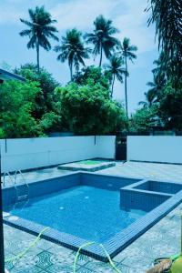 a swimming pool with palm trees in the background at Neon Villa in Pondicherry