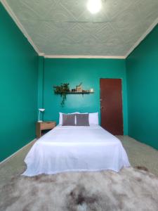 a bedroom with a white bed and a green wall at Pachamec House in Guayaquil