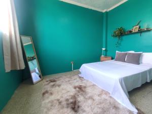 a bedroom with a white bed and a blue wall at Pachamec House in Guayaquil