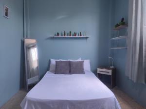a bedroom with a white bed and a blue wall at Pachamec House in Guayaquil