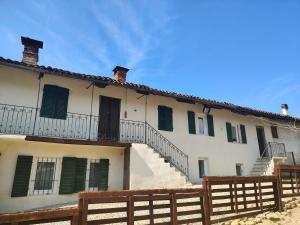 a building with green shutters and a wooden fence at Cascina Danila in Narzole
