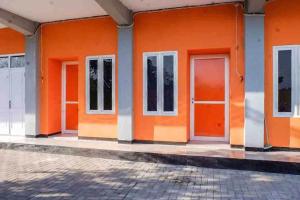 a row of orange doors on a building at Artayya Puri 2 near Alun Alun Caruban Mitra RedDoorz in Madiun