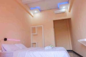 a room with two beds and a door with blue lights at Artayya Puri 2 near Alun Alun Caruban Mitra RedDoorz in Madiun +19 photos