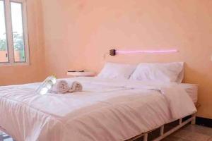 a bedroom with a white bed with shoes on it at Artayya Puri 2 near Alun Alun Caruban Mitra RedDoorz in Madiun
