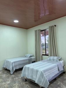 two beds in a room with a window at Hospedaje Alejandra in Canoas