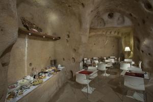 un restaurante con mesas blancas y aseos en una cueva en Antico Convicino Rooms Suites & SPA en Matera