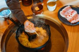 a person cooking food in a pot on a stove at 囲み宿 こわね in Tonosho +46 photos