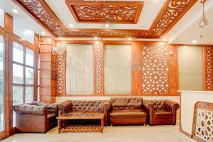 a living room with brown leather furniture and windows at Townhouse Oak Dehradun Court Formerly GK Residency in Dehradun