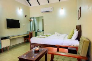 a room with a bed and a table and a tv at Green Planet Resort in Mattanūr