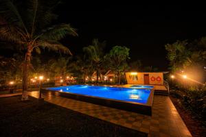 a swimming pool at night with palm trees and lights at Green Planet Resort in Mattanūr
