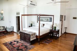a bedroom with a canopy bed and a wooden floor at Villa Sayura by TONIK, Boossa - Beachfront in Busse