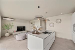 a kitchen with a white island in a living room at Luxury Two-Bedroom Apartments at Blue Bay The Breeze in Dorp Sint Michiel