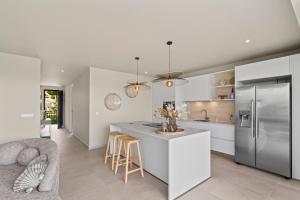 a kitchen with a refrigerator and a counter with chairs at Luxury Two-Bedroom Apartments at Blue Bay The Breeze in Dorp Sint Michiel