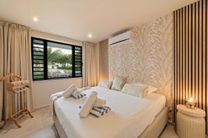 a bedroom with a large white bed and a window at Luxury Two-Bedroom Apartments at Blue Bay The Breeze in Dorp Sint Michiel +33 photos