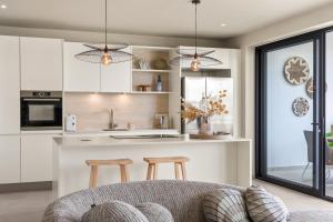 a kitchen with white cabinets and a counter with stools at Luxury Two-Bedroom Apartments at Blue Bay The Breeze in Dorp Sint Michiel