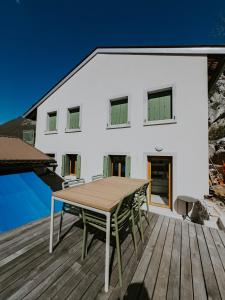 a white house with a wooden table on a deck at Up and above in Kobarid