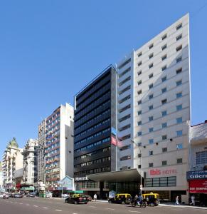 a large building on a city street with cars at ibis Buenos Aires Obelisco in Buenos Aires