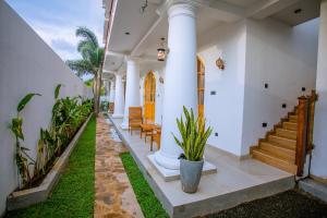 a house with white walls and a porch with plants at King Palace Mirissa in Mirissa