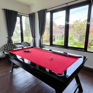 a red pool table in a room with windows at Sierra by Semusim Villa in Cianjur