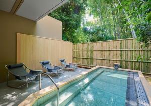 a swimming pool with two chairs and a fence at Fufu Atami in Atami