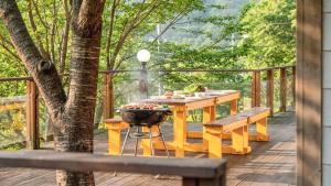 a wooden deck with a grill and a table and benches at Mungyeong Between Mountains Pet Pension in Mungyeong