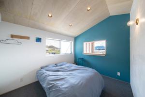 ein Schlafzimmer mit blauen Wänden und einem Bett darin in der Unterkunft NOMAyado in Naruto
