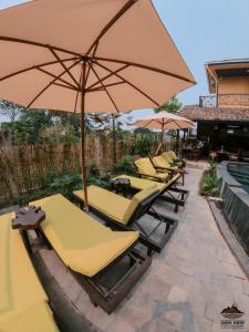 a row of lounge chairs with an umbrella at Trang An Ninh Binh Rustic Hideaway in Ninh Binh