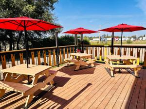 three picnic tables and red umbrellas on a deck at Theodore Motor Hotel in Theodore